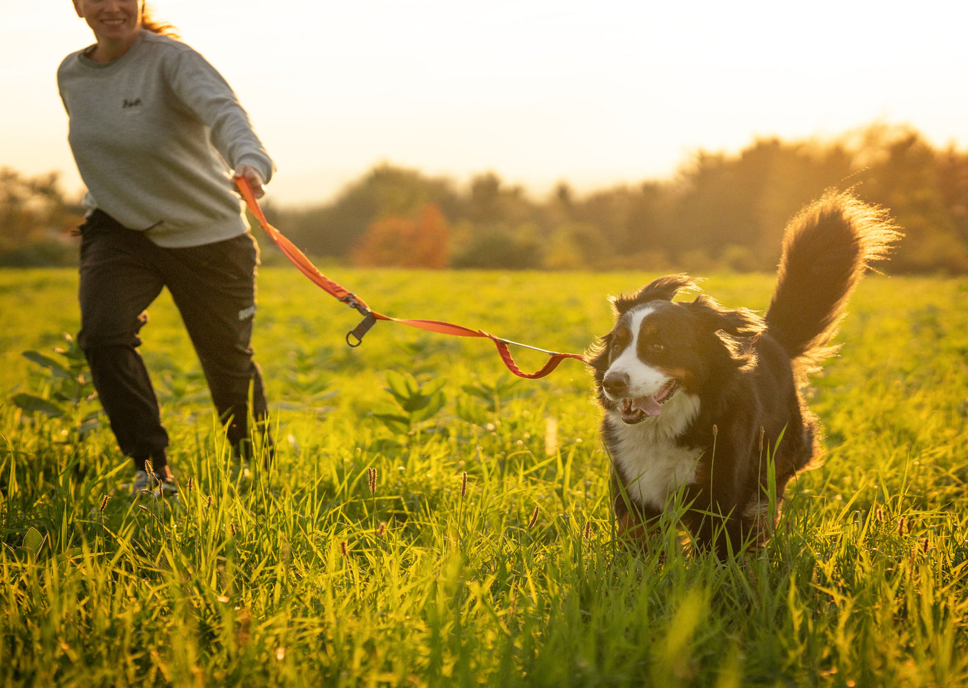 A woman and her dog in a field with Nuvuq Multifunctional Orange Leash 