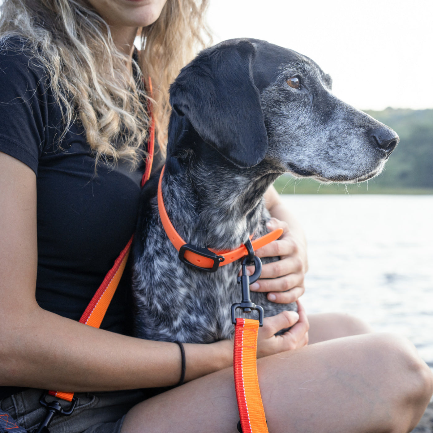 Woman and her large dog tied with a multifunctional orange Nuvuq leash matched with a water-resistant Nuvuq Large collar